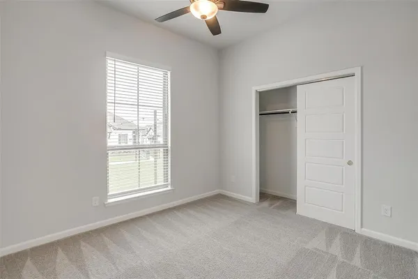 an empty room with chandelier fan and windows