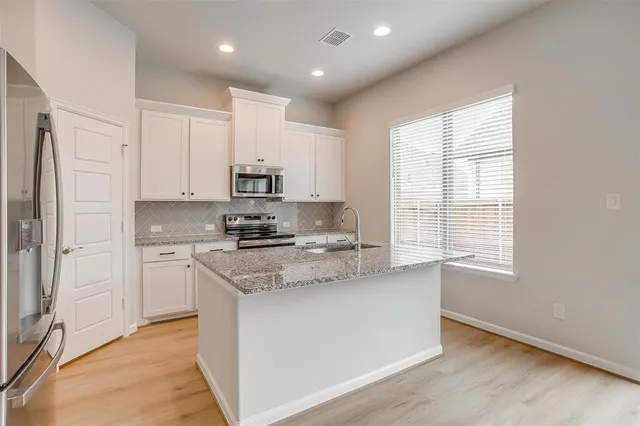 a kitchen with stainless steel appliances granite countertop a sink a stove a refrigerator and cabinets