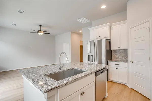 a kitchen with stainless steel appliances granite countertop a sink refrigerator and cabinets