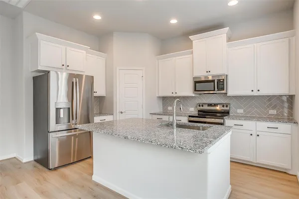a kitchen with stainless steel appliances granite countertop a stove a sink a refrigerator and white cabinets