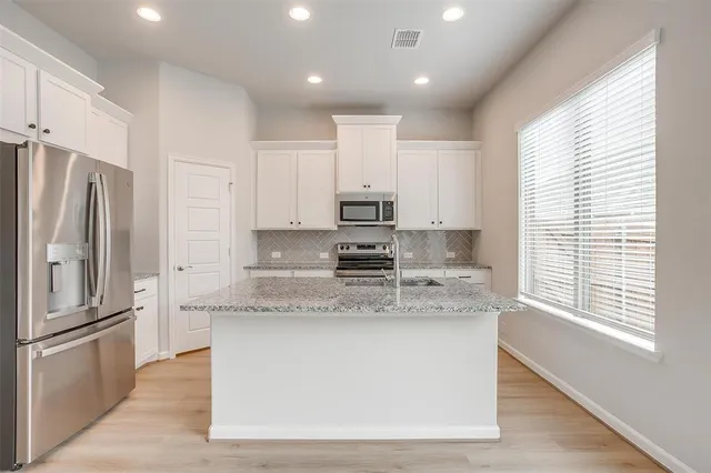 a large kitchen with stainless steel appliances granite countertop a stove a sink and a refrigerator