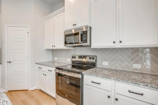 a kitchen with granite countertop white cabinets and stainless steel appliances