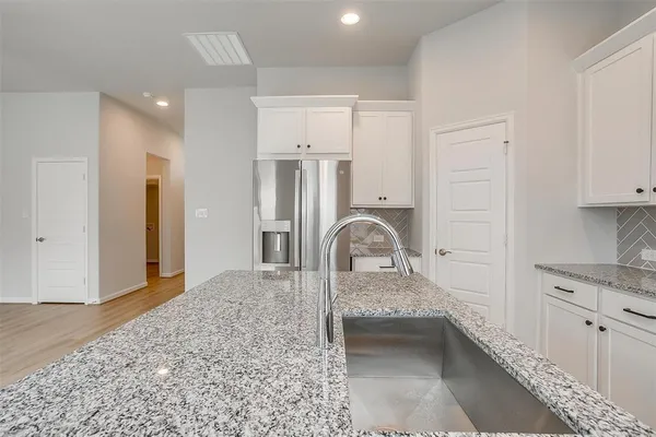 a kitchen with stainless steel appliances granite countertop a refrigerator a sink and white cabinets