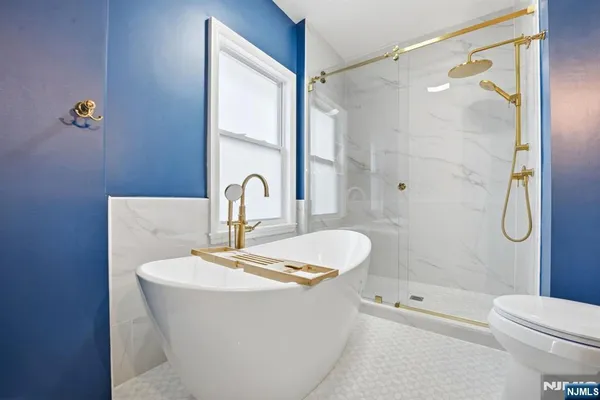 a bathroom with a white bath tub a mirror and a shower