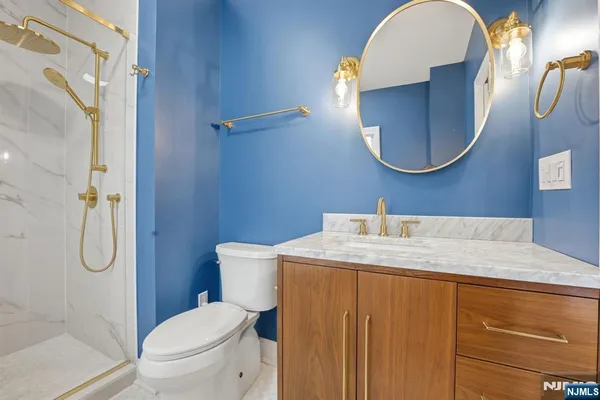 a bathroom with a granite countertop toilet sink vanity and mirror