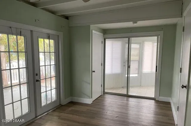 a view of an empty room with wooden floor and a window
