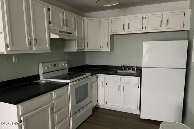 a kitchen with stainless steel appliances granite countertop white cabinets stove a sink and dishwasher