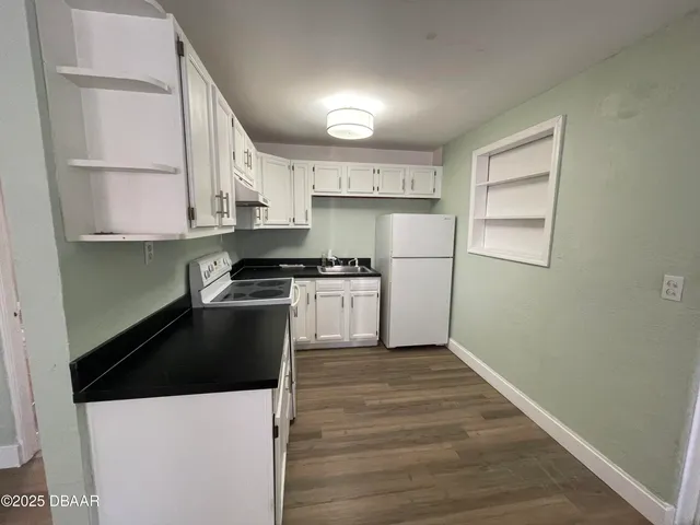 a kitchen with granite countertop a stove a sink and a refrigerator