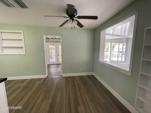 a view of empty room with wooden floor and fan