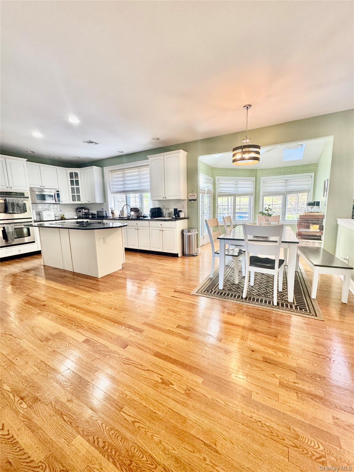 194 Devon Farms Road Stormville, NY 12582 - Photo 13 of 37 a view of a kitchen with kitchen island a stove a counter space cabinets and a dining table with chairs
