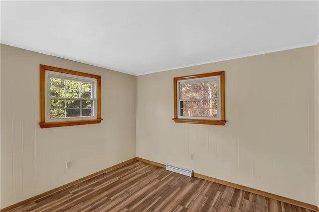 a view of an empty room with window and wooden floor