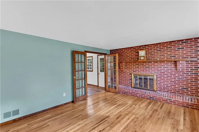 a view of an empty room with wooden floor and a fireplace