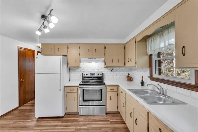 a kitchen with a sink dishwasher a refrigerator a stove and white cabinets with wooden floor