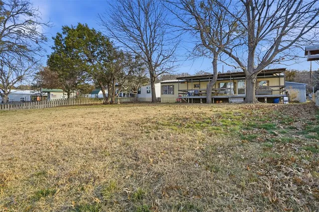 a backyard of a house with large trees and outdoor seating