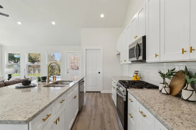 a kitchen with granite countertop a sink a stove and cabinets
