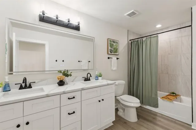 a bathroom with a granite countertop sink a toilet a mirror and shower