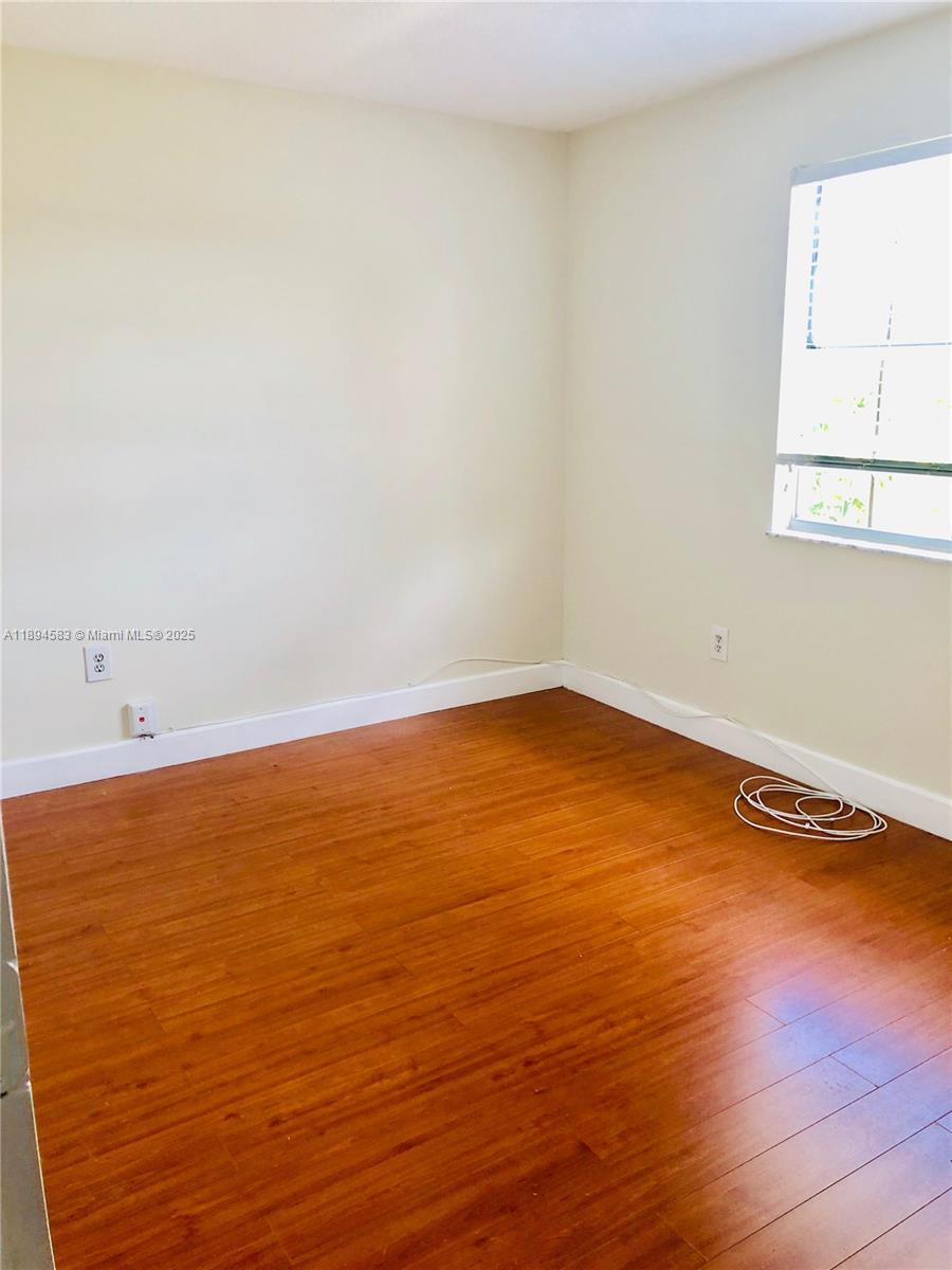 1010 Southwest 99th Avenue Pembroke Pines, FL 33025 - Photo 18 of 22 an empty room with wooden floor and windows