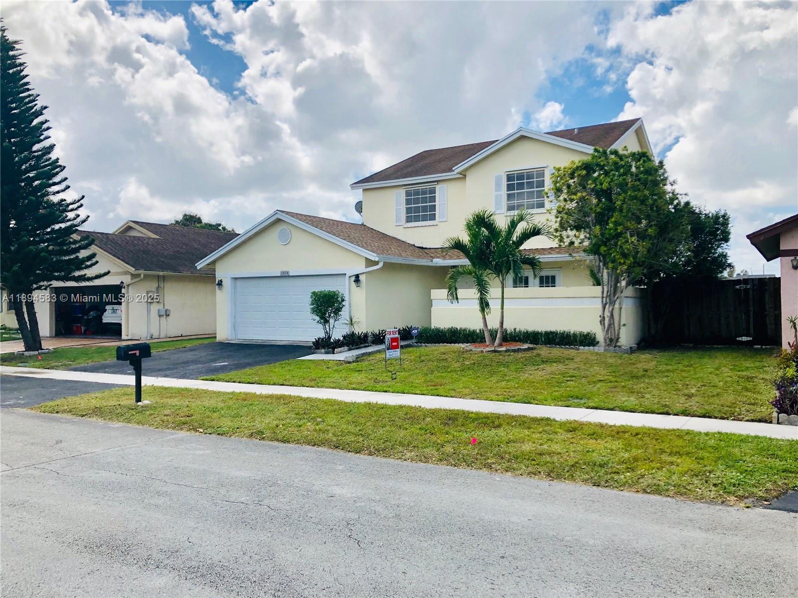 1010 Southwest 99th Avenue Pembroke Pines, FL 33025 - Photo 2 of 22 a front view of a house with a yard and garage