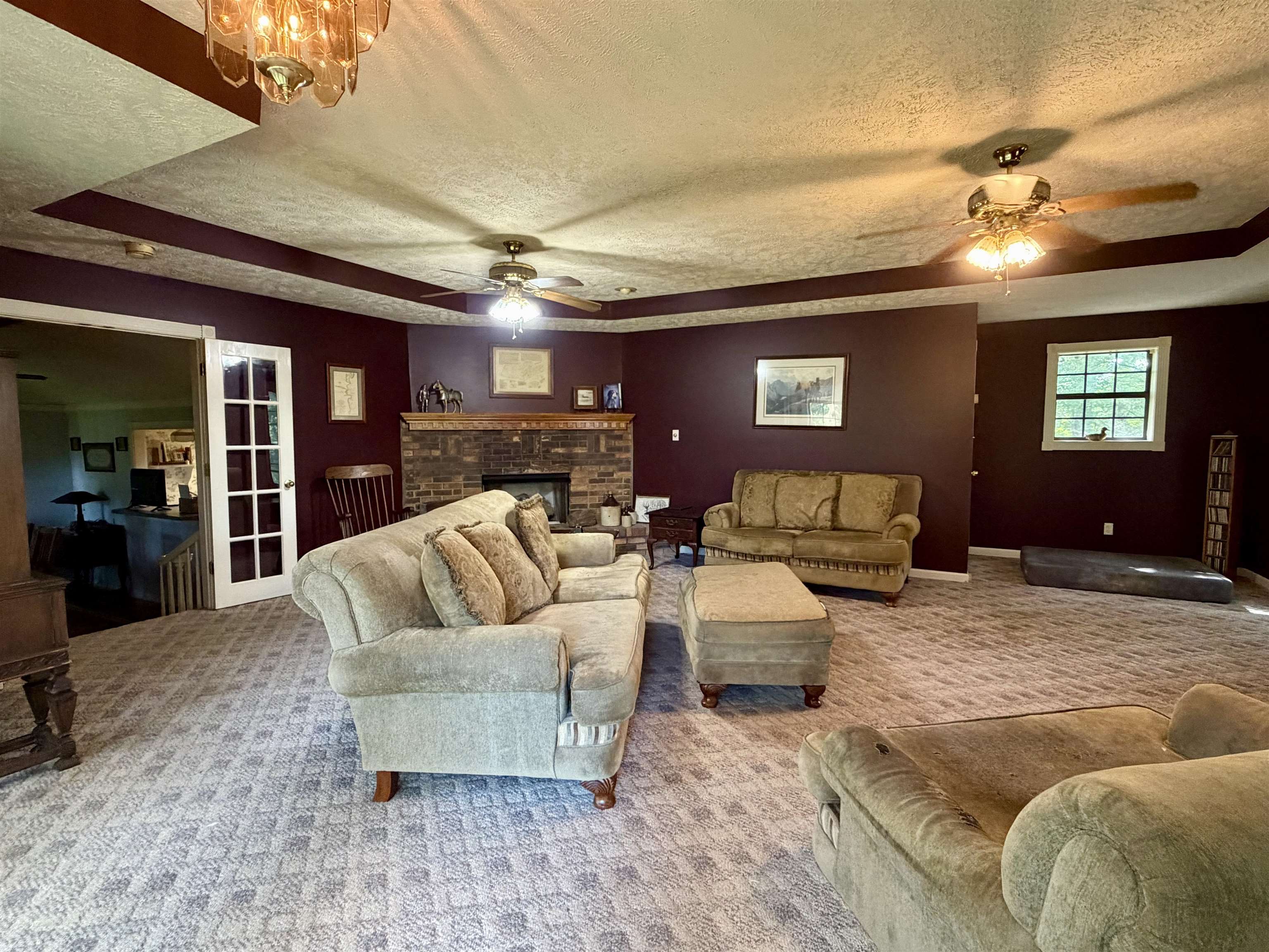 373 Clarence Barham Road Bethel Springs, TN 38315 - Photo 3 of 28 Spacious living area featuring patterned carpeting, a brick fireplace, and multiple ceiling fans
