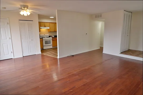 an empty room with wooden floor closet and windows