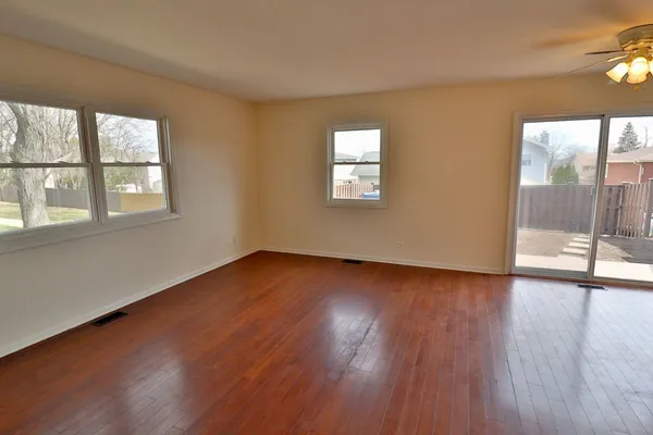 a view of an empty room with wooden floor and a window