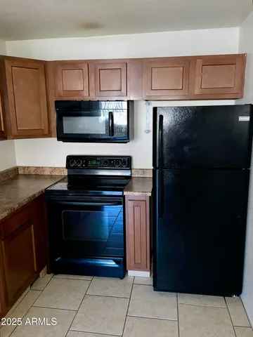 a kitchen with granite countertop a refrigerator and a cabinets