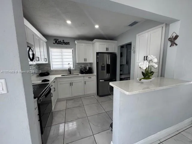 a kitchen with a sink a refrigerator and cabinets