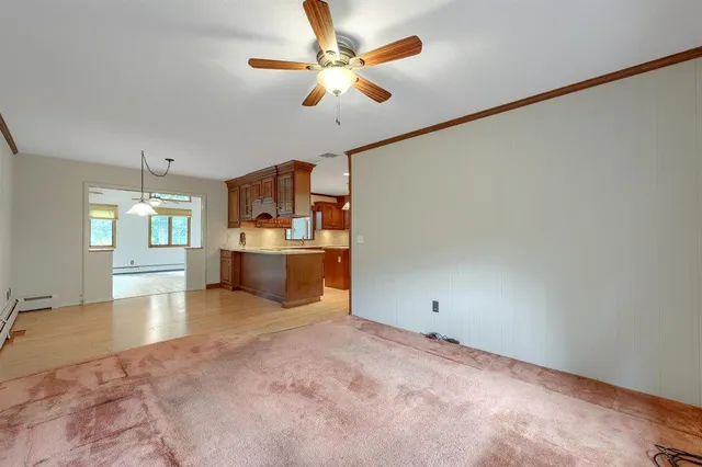 an empty room with a chandelier fan and windows