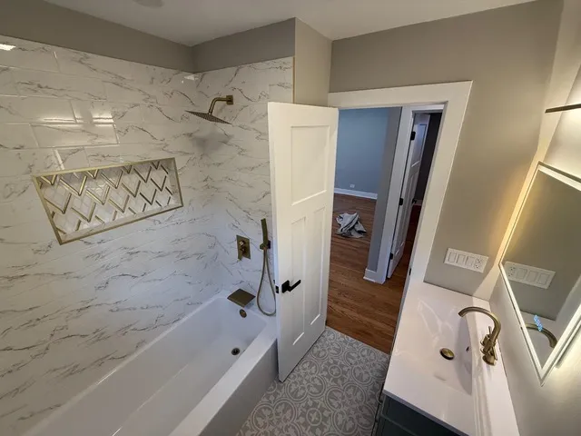 a bathroom with a tub a sink and a mirror