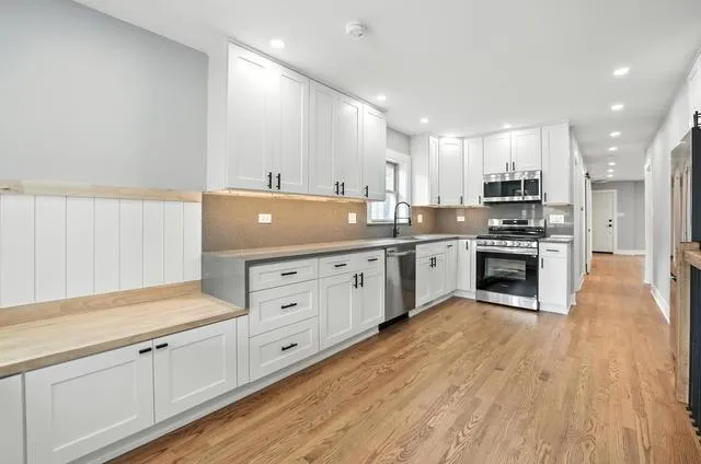 a kitchen with stainless steel appliances granite countertop a sink a stove and a refrigerator