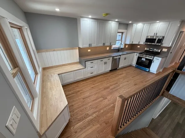 a large white kitchen with a sink and dishwasher a stove top oven with wooden floor