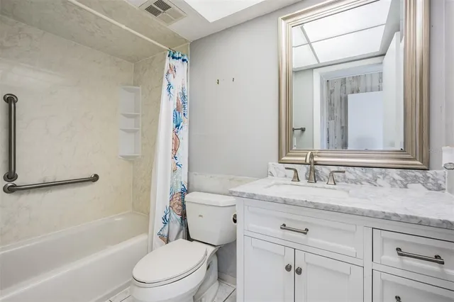 a bathroom with a granite countertop toilet sink and mirror