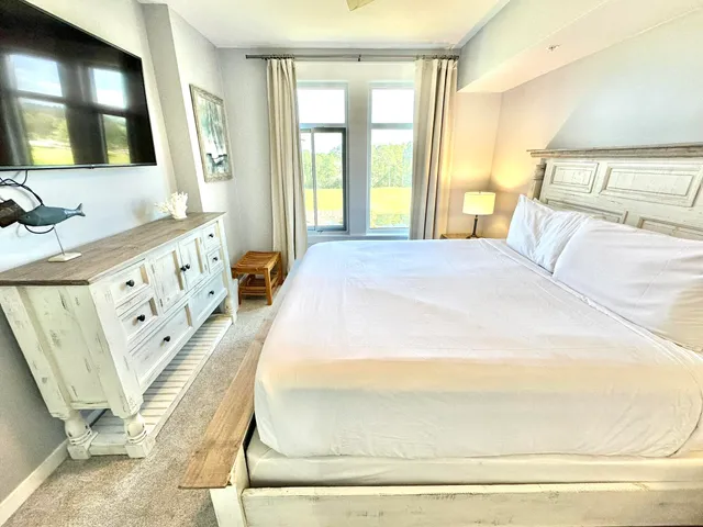 a bedroom with a bed and a flat tv screen on dresser