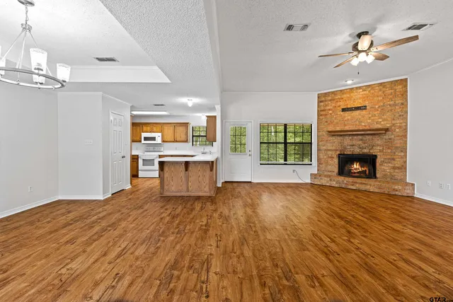 a view of a livingroom with a fireplace wooden floor cabinet and windows