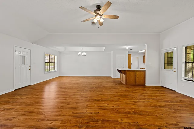 a view of empty room with wooden floor and fan