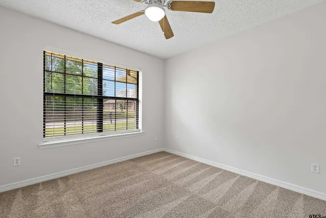 an empty room with windows and fan