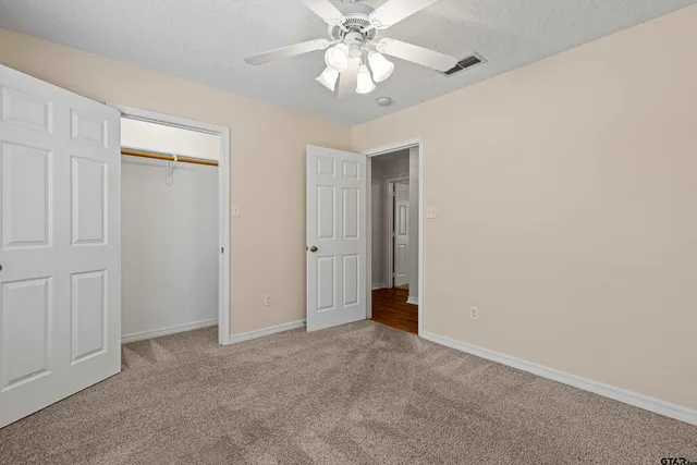 a view of an empty room and chandelier fan