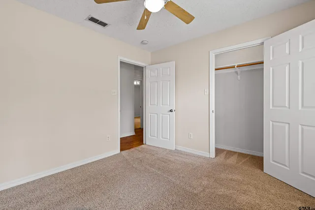 an empty room with closet and a chandelier fan