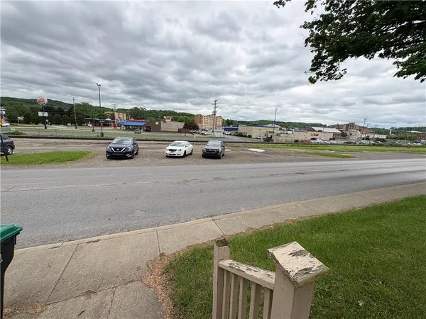 a view of a car parked on the side of the road with big trees