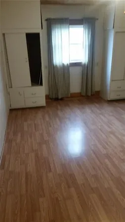 a view of an empty room with wooden floor and windows