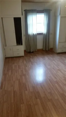 a view of an empty room with wooden floor and windows