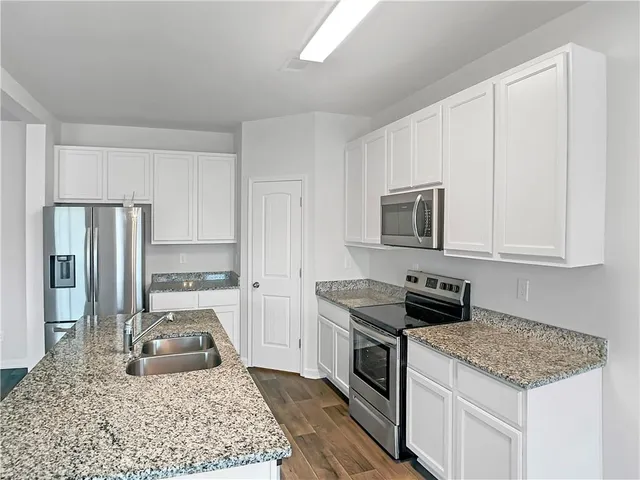 a kitchen with granite countertop a sink stove and refrigerator