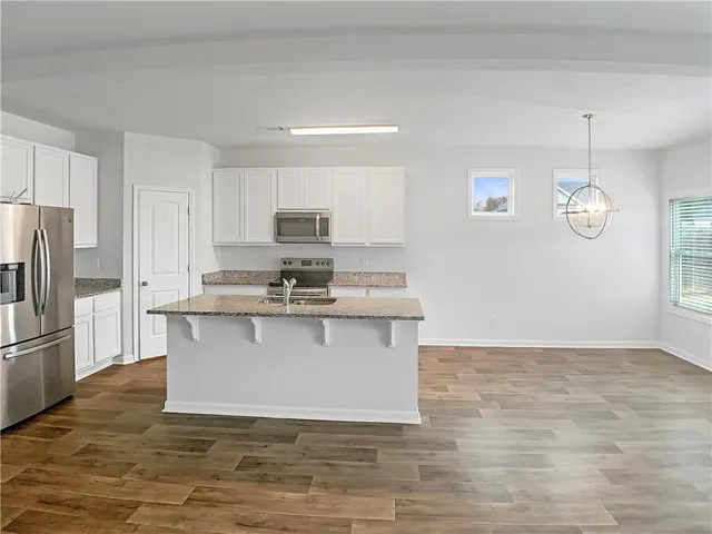 a view of kitchen with microwave stove refrigerator and cabinets