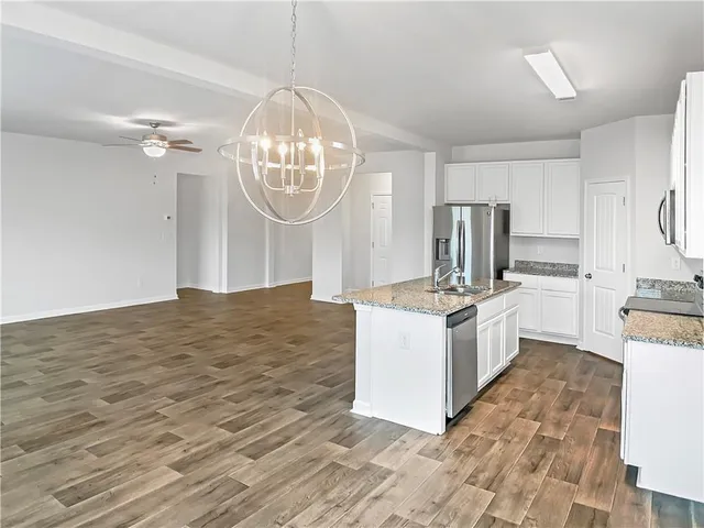 a kitchen with granite countertop a stove a sink dishwasher a refrigerator and a dining table with wooden floor