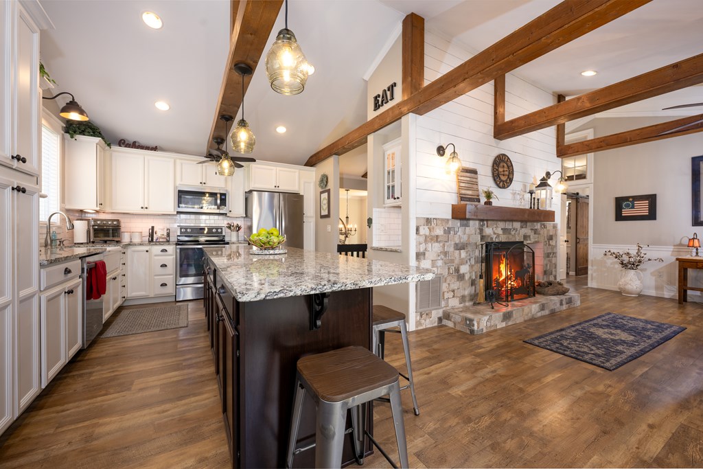 3301 Ellington Road Hayesville, NC 28904 - Photo 6 of 31 a open kitchen with stainless steel appliances granite countertop a stove top oven a sink dishwasher and a fireplace with wooden floor