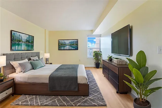 a bedroom with a bed table couch and a potted plant