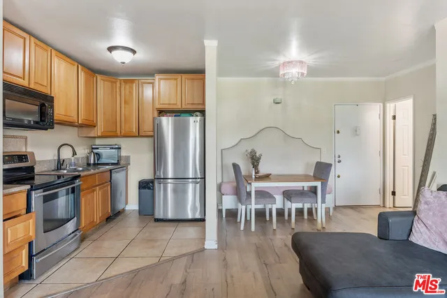 a kitchen with stainless steel appliances granite countertop a refrigerator a stove a sink a dining table and chairs with wooden floor