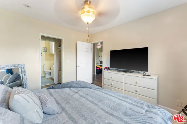 a bedroom with bed flat screen tv and a chandelier