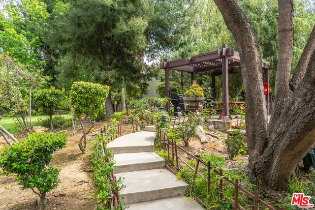 a view of a balcony with chairs potted plants and large tree