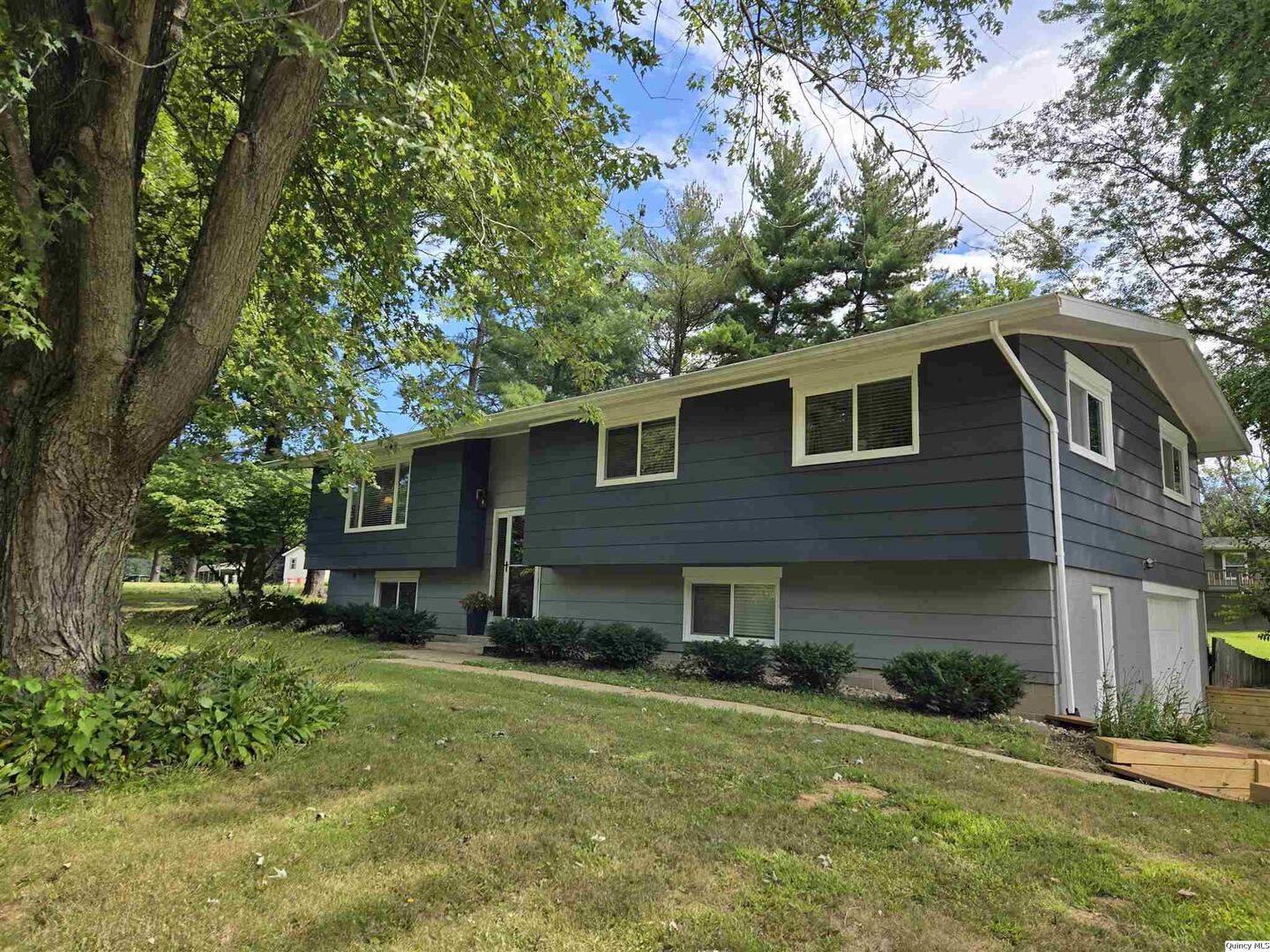 a front view of a house with a garden and trees